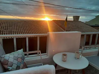 a sunset on a balcony with a table and a chair at Casa Tropicana in Paul do Mar