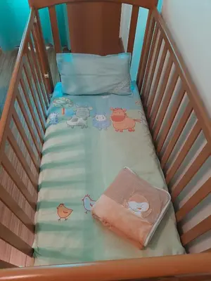 a crib with a bedsheet with animals on it at Residência do Saramago in São Vicente