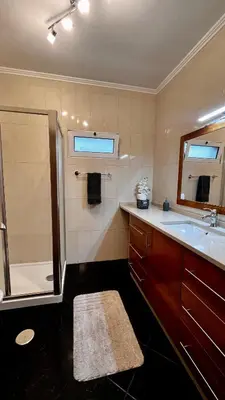 a bathroom with a shower and a sink and a mirror at Residência do Saramago in São Vicente