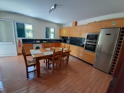 a kitchen with a table and chairs and a refrigerator at Residência do Saramago in São Vicente