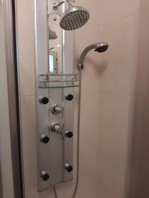 a shower stall with a shower head and a mirror at Residência do Saramago in São Vicente