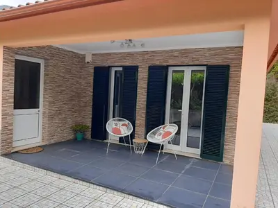 two chairs sitting on a patio with a house at Residência do Saramago in São Vicente