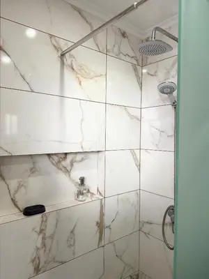 a bathroom with a shower with marble tiles at Gouveia Family Escape in Machico
