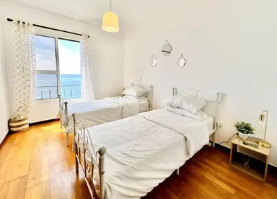two beds in a bedroom with a view of the ocean at Apartment Paulo by Your Madeira Rentals in Ponta do Sol