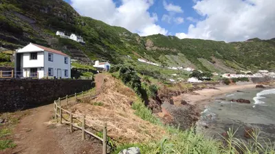 a white house on a hill next to a beach at Casa da Ponta Negra in Vila do Porto