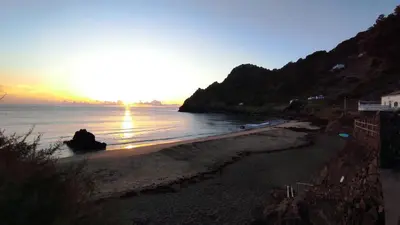 a beach with the sun setting on the water at Casa da Ponta Negra in Vila do Porto