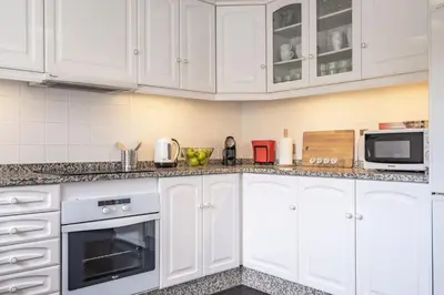 a white kitchen with white cabinets and appliances at Casa da Palmeira in Funchal