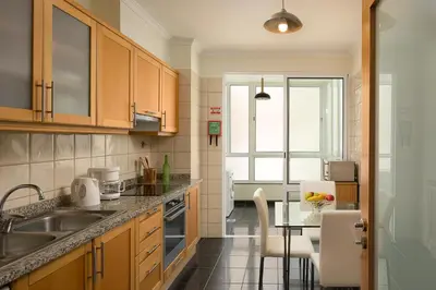 a kitchen with wooden cabinets and a table and a counter top at Apartamento Vale e Mar in Calheta