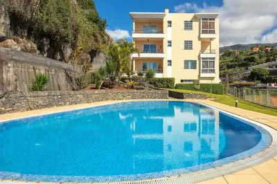 a large blue swimming pool in front of a building at Apartamento Vale e Mar in Calheta