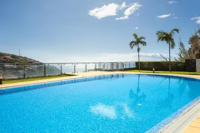 a large swimming pool with a view of the ocean at Apartamento Vale e Mar in Calheta