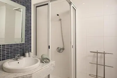 a white bathroom with a sink and a shower at Apartamento Vale e Mar in Calheta