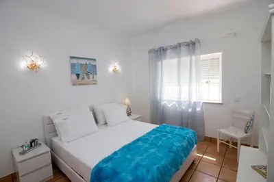 a white bedroom with a large bed and a window at Villa Ílios - Porto de Mós, Lagos in Lagos
