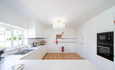 a white kitchen with a sink and a microwave at Villa Ílios - Porto de Mós, Lagos in Lagos