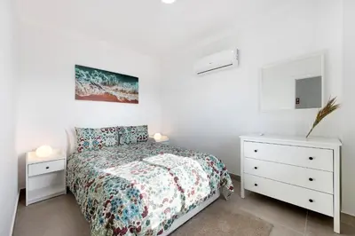 a white bedroom with a bed and two night stands at Victoria's House in Sagres