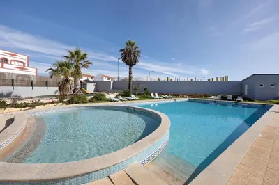 a large swimming pool with palm trees and a building at Victoria's House in Sagres