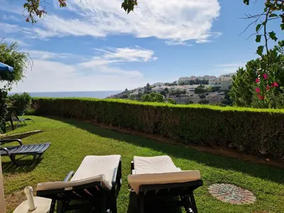 two chairs and tables on a lawn with a view of the ocean at Amazing Studio with Ocean View in Lagos