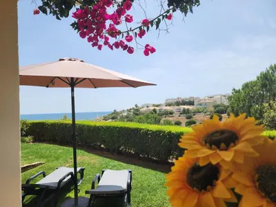a patio with an umbrella and chairs and a sunflower at Amazing Studio with Ocean View in Lagos