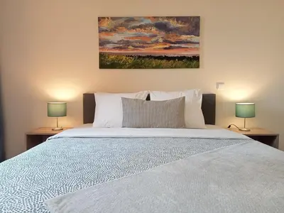 a bedroom with a large bed with two lamps at Sunrise Apartment in Caniço