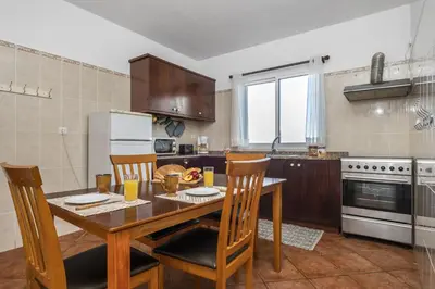 a kitchen with a wooden table and chairs and a kitchen with a refrigerator at Green Valley by Homie in Porto Moniz
