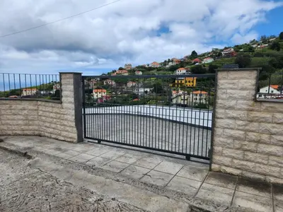 a gate with a view of a body of water at Blue Horizon, Sea and Mountain view in Estreito da Calheta