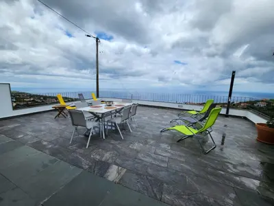 a patio with a table and chairs on a balcony at Blue Horizon, Sea and Mountain view in Estreito da Calheta