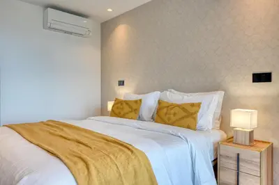 a bedroom with a bed with white sheets and yellow pillows at Becas Place, a Home in Madeira in Funchal