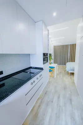 a kitchen with white cabinets and a living room at Vista Oceano IV in Caniço