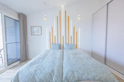 a large bed in a white room with chandeliers at Vista Oceano IV in Caniço