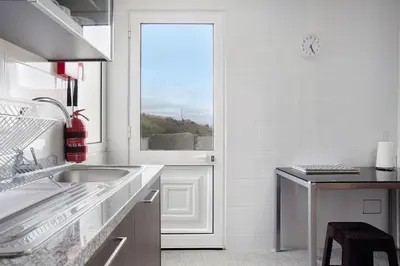 a white kitchen with a sink and a window at Simão House in Calheta