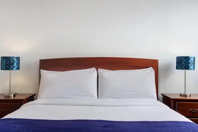 a bed with white pillows and two lamps on tables at Simão House in Calheta