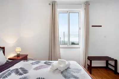 a bedroom with a bed with a window at Simão House in Calheta