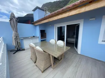 a table and chairs on a balcony with a house at Tides proprety - High tide in Paul do Mar