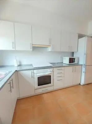 a kitchen with white cabinets and a stove top oven at Desertrose in Porto Santo