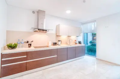 a kitchen with wooden cabinets and a large window at Suite BM - 3 Pools-Gym-AC-Huge Balcony Sea View in Funchal