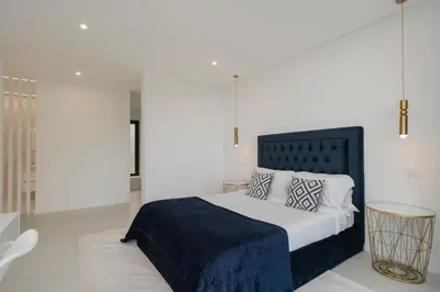 a bedroom with a bed with a blue blanket and pillows at The White House by An Island Apart in Ponta do Sol