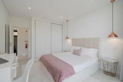 a white bedroom with a bed and a table and chairs at The White House by An Island Apart in Ponta do Sol