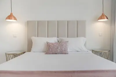 a bedroom with a large white bed with two tables at The White House by An Island Apart in Ponta do Sol