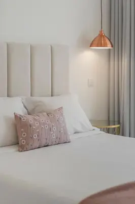 a bedroom with a white bed with a pink pillow at The White House by An Island Apart in Ponta do Sol