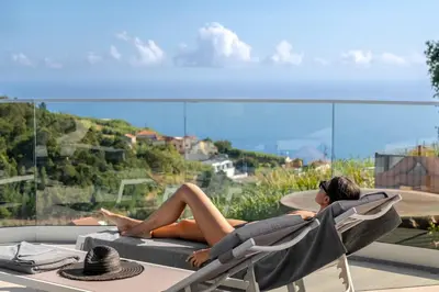 a woman laying in a chair on a balcony at The White House by An Island Apart in Ponta do Sol