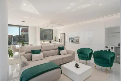 a living room with a couch and green chairs at The White House by An Island Apart in Ponta do Sol