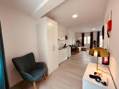 a living room with a green chair and a kitchen at Living Funchal iNN in Funchal