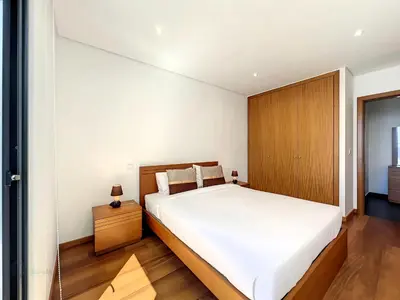 a bedroom with a white bed and a wooden cabinet at Casa Dream 2 in Calheta