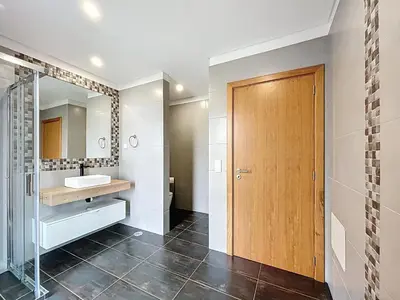 a bathroom with a sink and a shower and a wooden door at Casa Dream 2 in Calheta