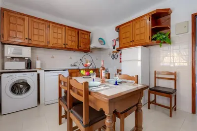 a kitchen with a table and chairs and a dishwasher at Casa Teresinha - V028 in Montinhos da Luz