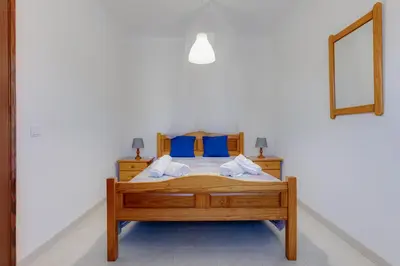 a bedroom with a bed with blue pillows and a mirror at Casa Teresinha - V028 in Montinhos da Luz