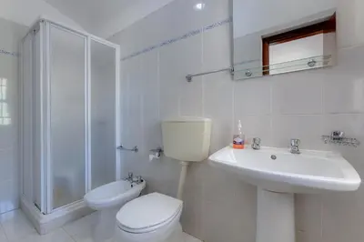 a white bathroom with a toilet and a sink at Casa Teresinha - V028 in Montinhos da Luz