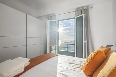 a bedroom with a bed and a large window at Il Tramonto by Homie in Ribeira Brava