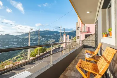 two wooden chairs on a balcony with a view at Il Tramonto by Homie in Ribeira Brava