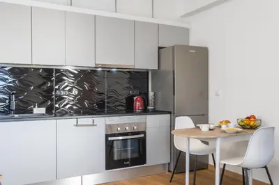 a kitchen with white cabinets and a table with chairs at Il Tramonto by Homie in Ribeira Brava