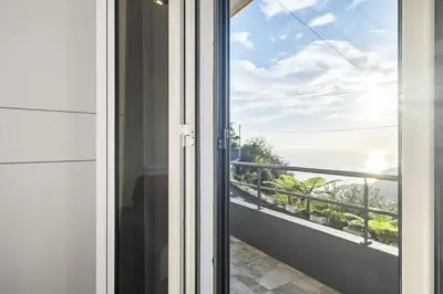 a door to a balcony with a view of the ocean at Il Tramonto by Homie in Ribeira Brava
